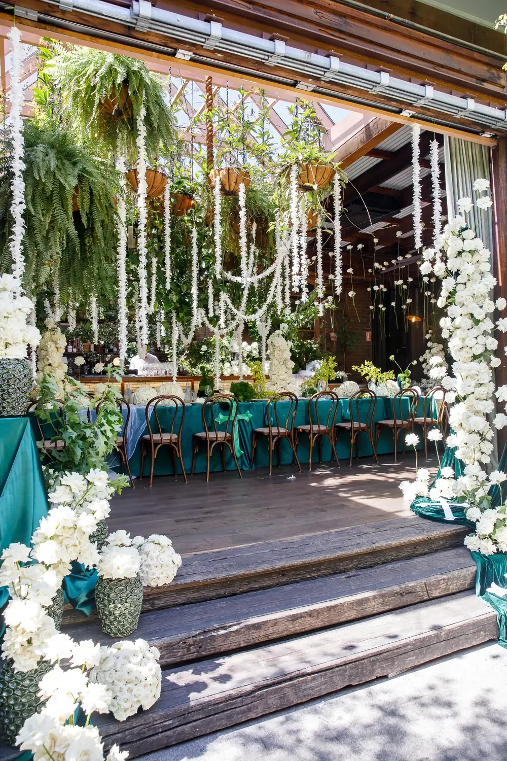 Luxury christening venue styling with cascading white floral installations and greenery at event entrance