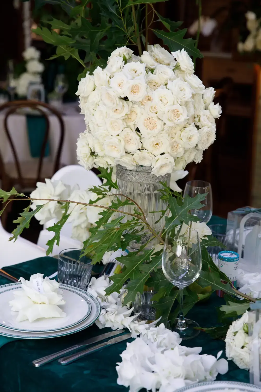 Classic white rose bouquet centrepiece with greenery on luxury christening table setting