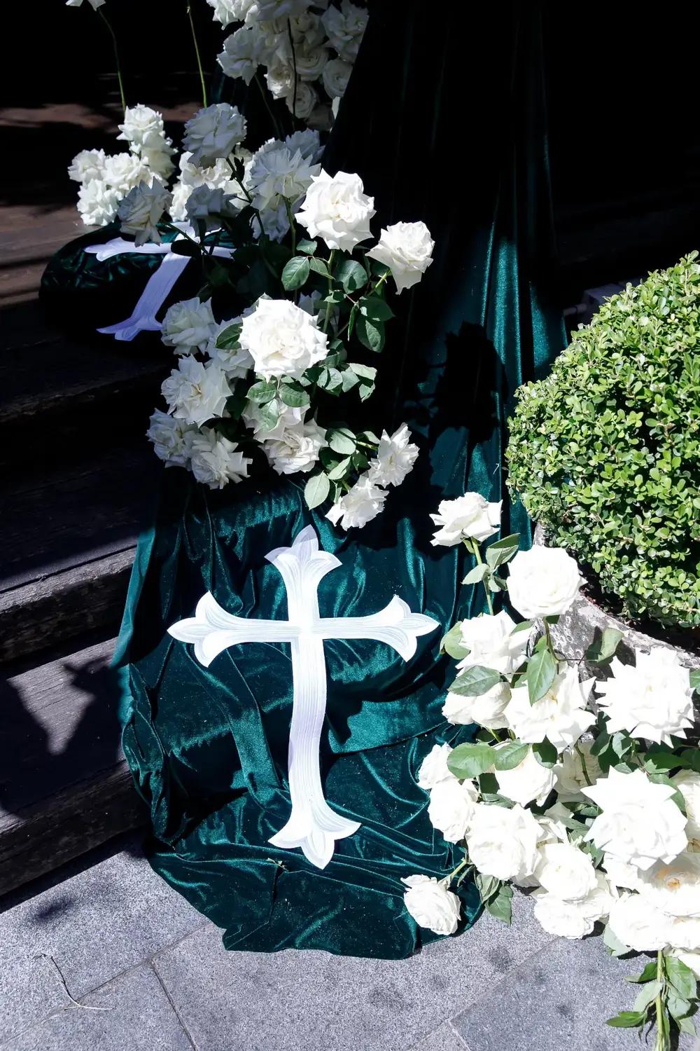 Christening floral detail with white roses and decorative cross styling on green draped table