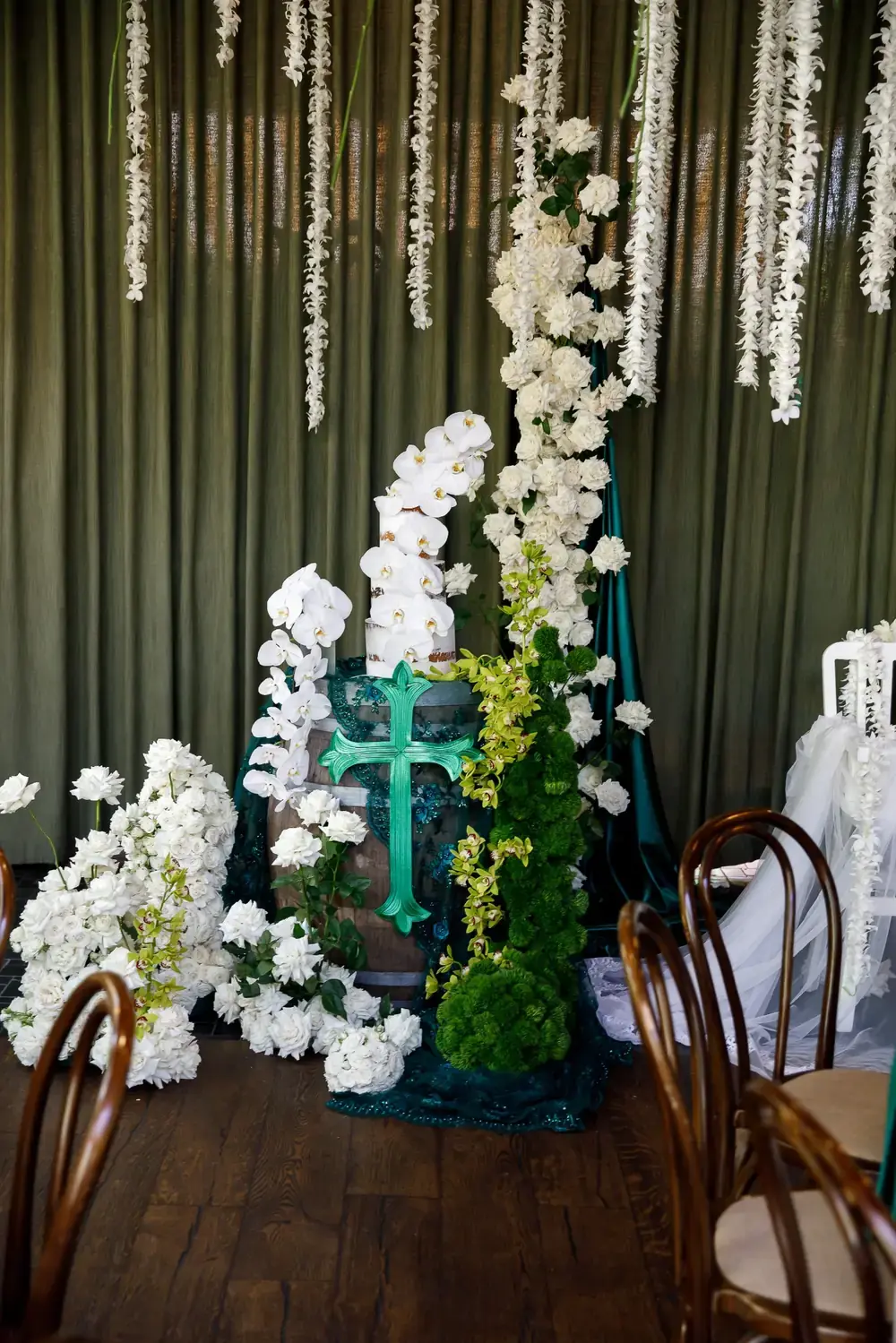 Christening cake table decorated with white flowers, orchids and greenery with statement cross feature