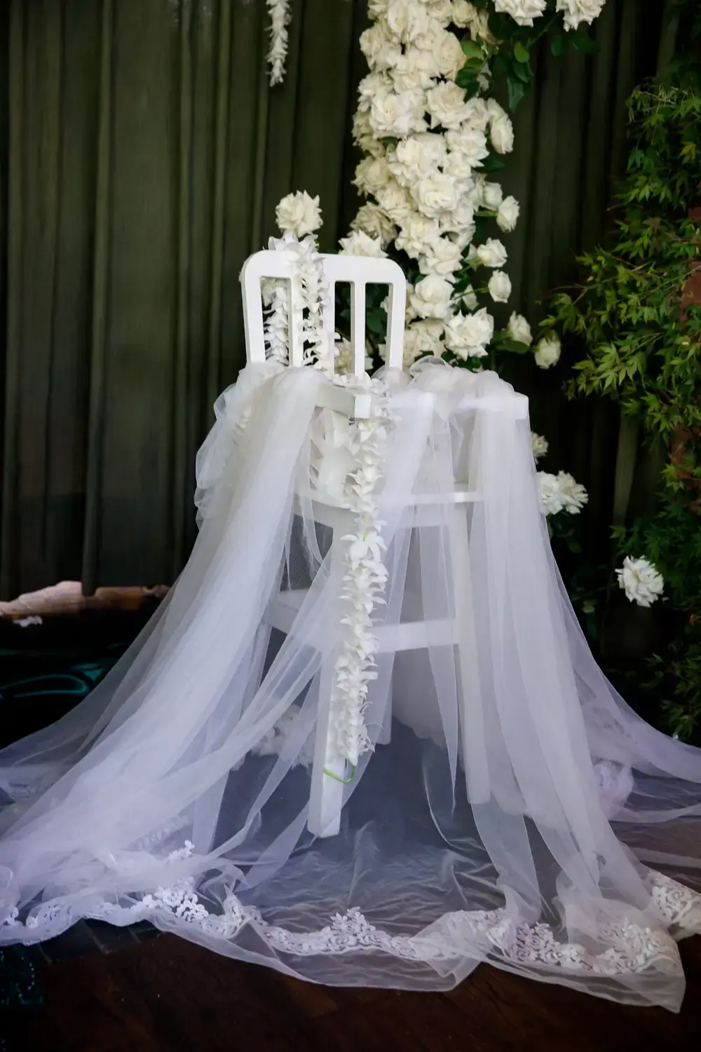 White chair styling with draped tulle and floral garland detail for christening ceremony setup