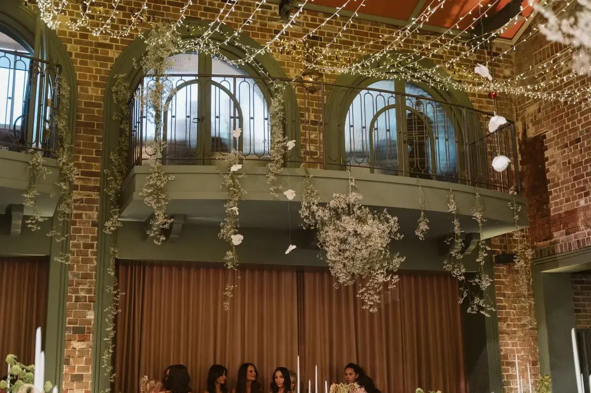 Hanging floral installations with fairy lights inside Linseed House wedding venue with exposed brick walls