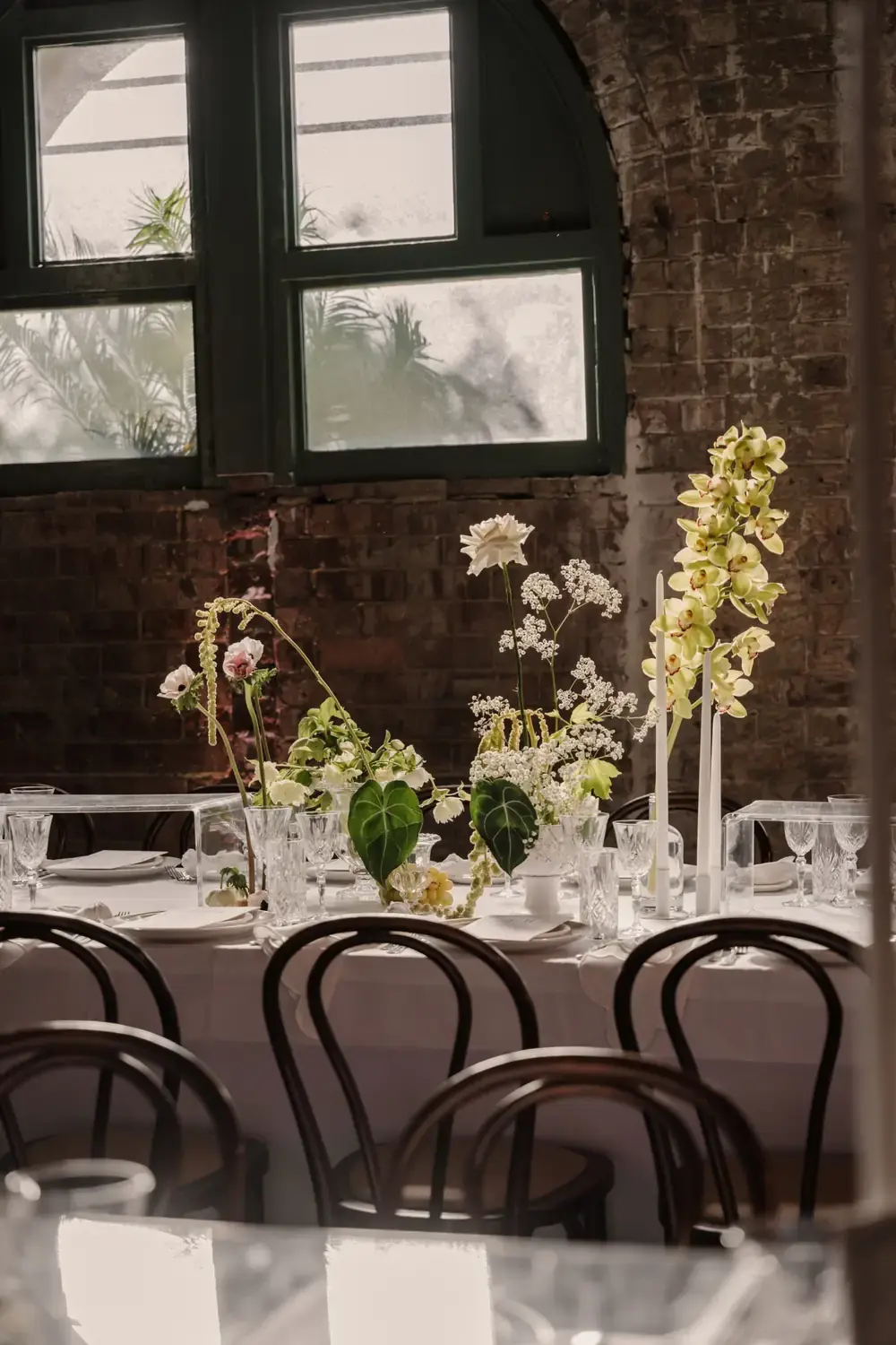 Wedding table centrepiece with orchids, white flowers and candles in elegant Linseed House setting