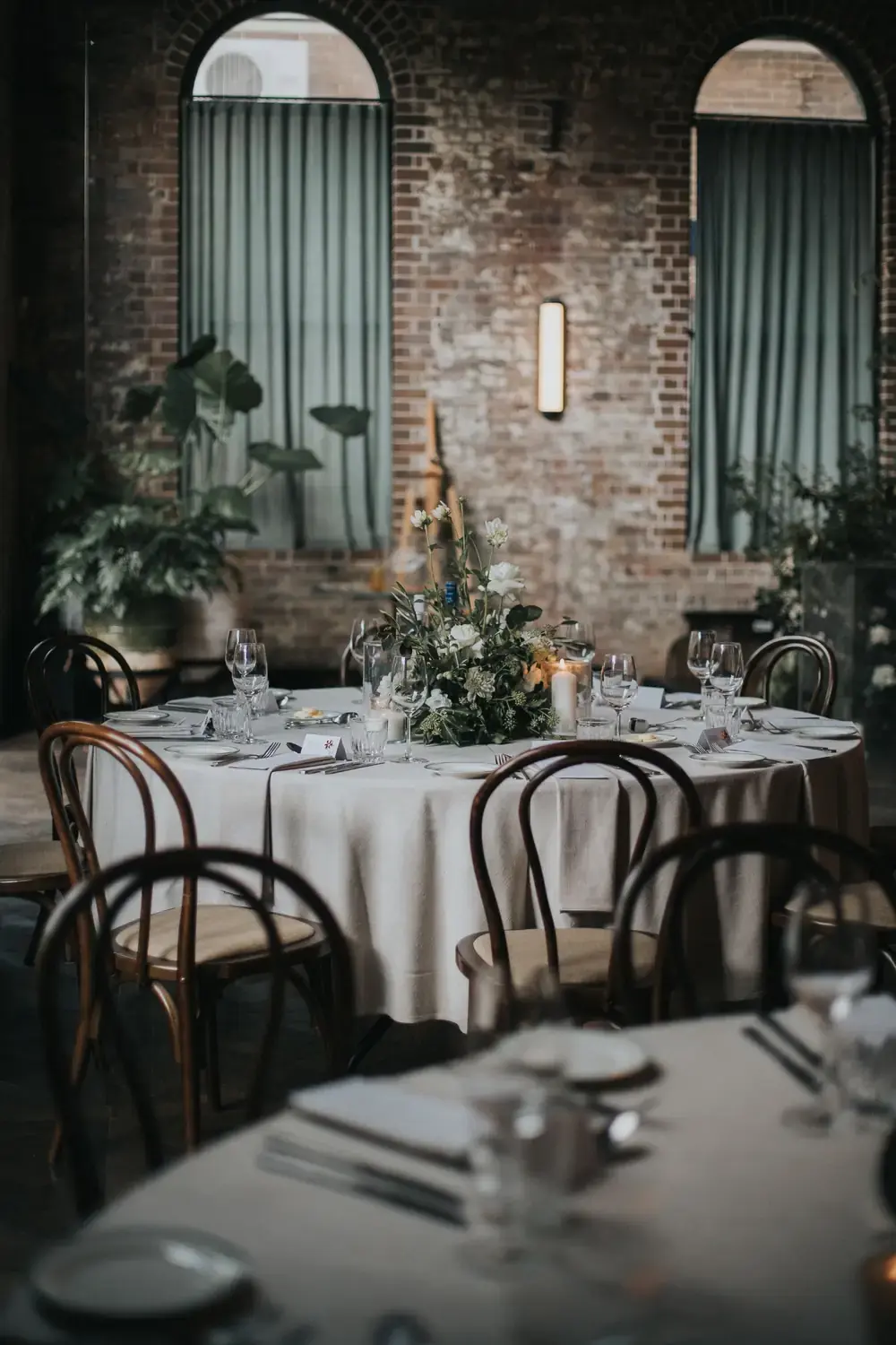 Elegant round reception table with white and green wedding flowers and candles at Linseed House