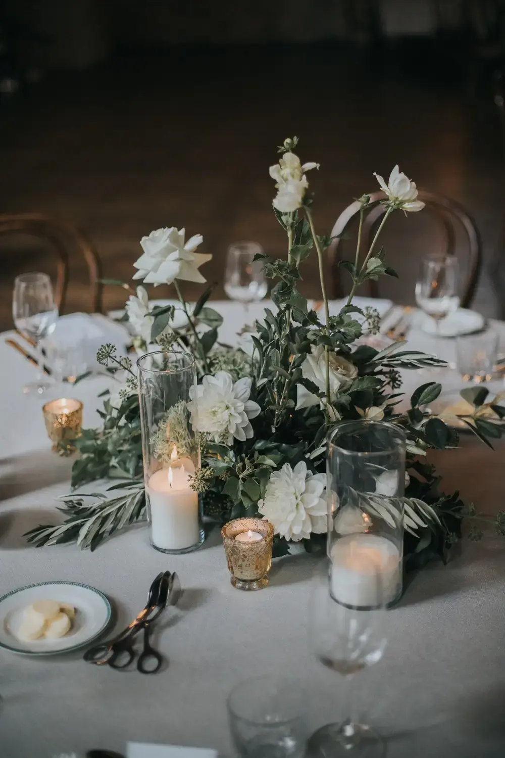 Detailed wedding flowers arrangement with candles and soft white florals on elegant reception table